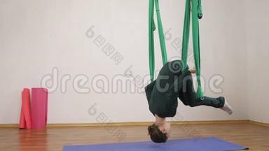 年轻的白种人妇女在<strong>室内</strong>工作室的<strong>吊床</strong>上做反重力飞行瑜伽练习。 航空飞行健身